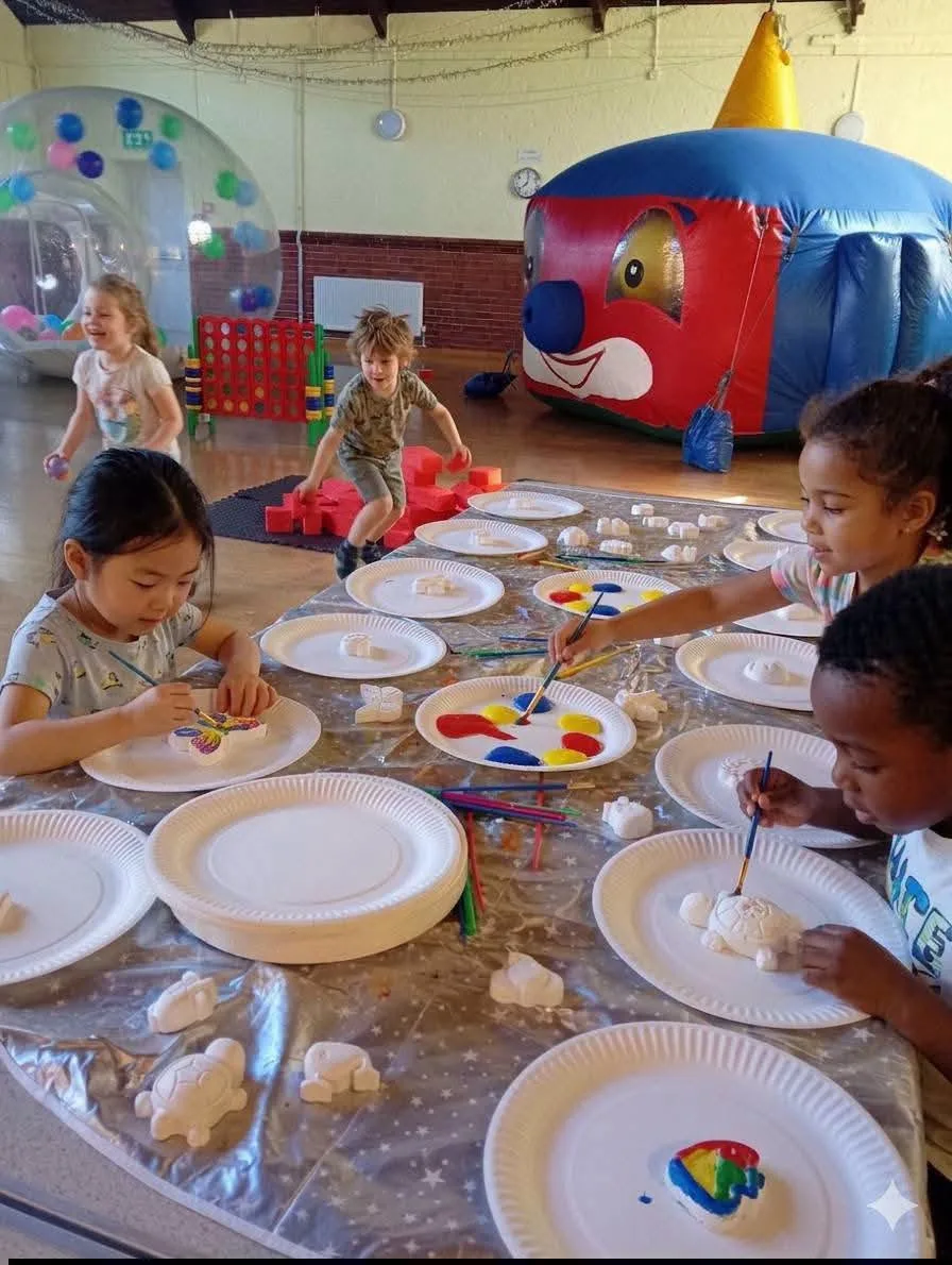 Children painting pottery shapes at a party table